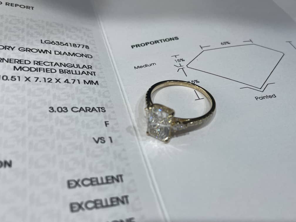 Diamond ring on top of a detailed certification report showing specifications and diagrams.